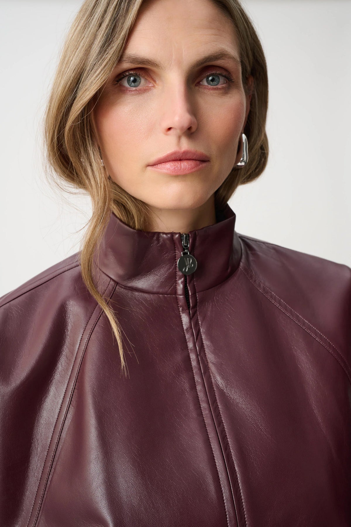 Close-up of neckline and upper-body details on Joseph Ribkoff Leatherette Mock-Neck Bomber Jacket in Burgundy, style 263971