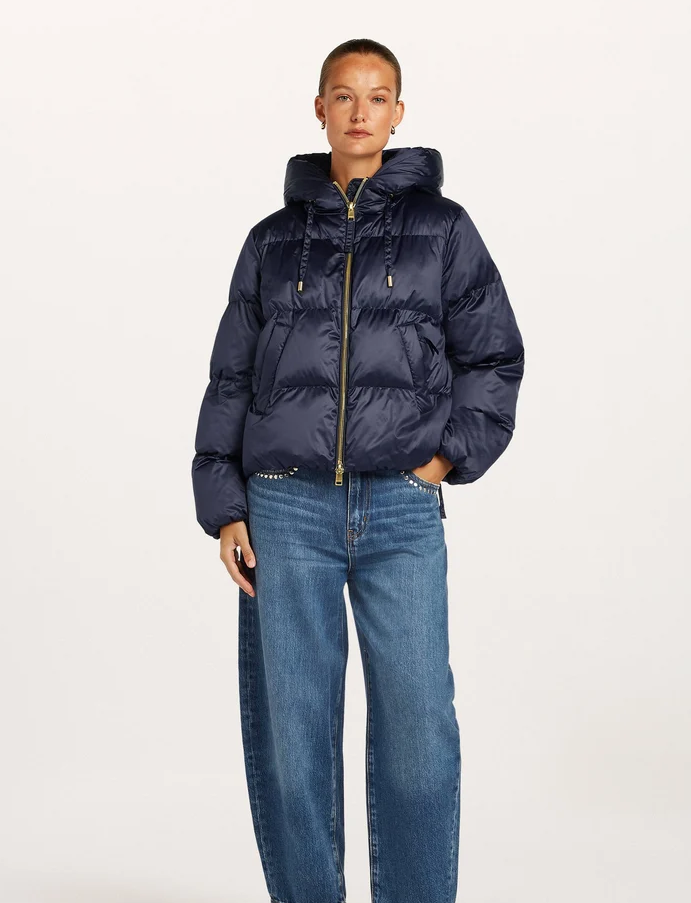 A model wearing a  beaumont marian navy jacket gold-tone hardware and blue jeans, standing against a plain white studio background.